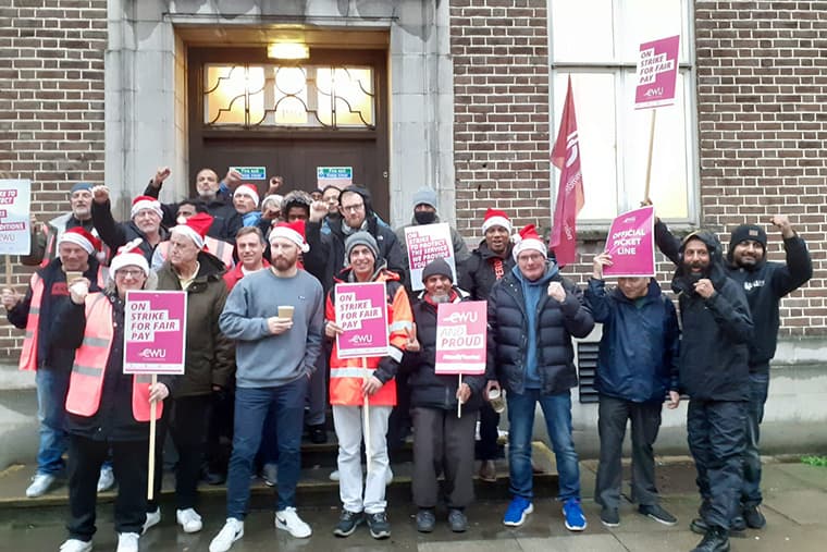 Des postiers sur une ligne de piquetage, dont beaucoup portent des chapeaux de Père Noël, illustrant un article sur les grèves de la Royal Mail